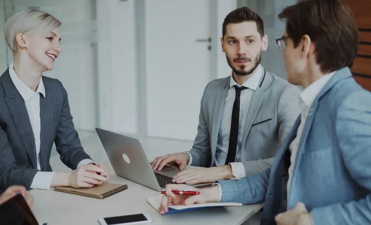 Business professionals in meeting with laptops discussing strategy